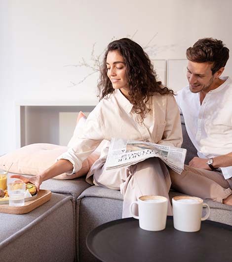 Zwei Personen frühstücken frische Brötchen auf der Couch